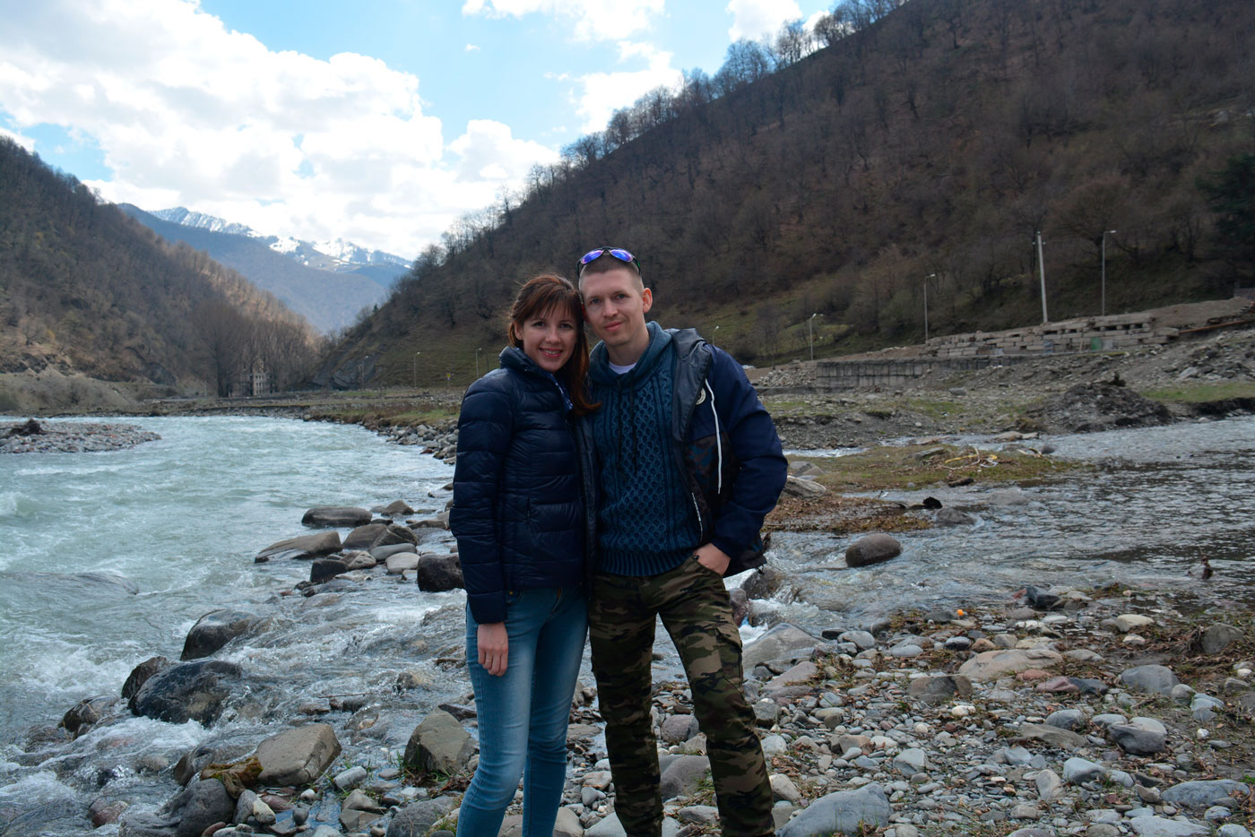 Мужчина и женщина на фоне горного пейзажа и бурлящей реки.